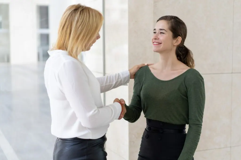 Counselor shaking hands with a young girl, promoting assertiveness and empowerment.