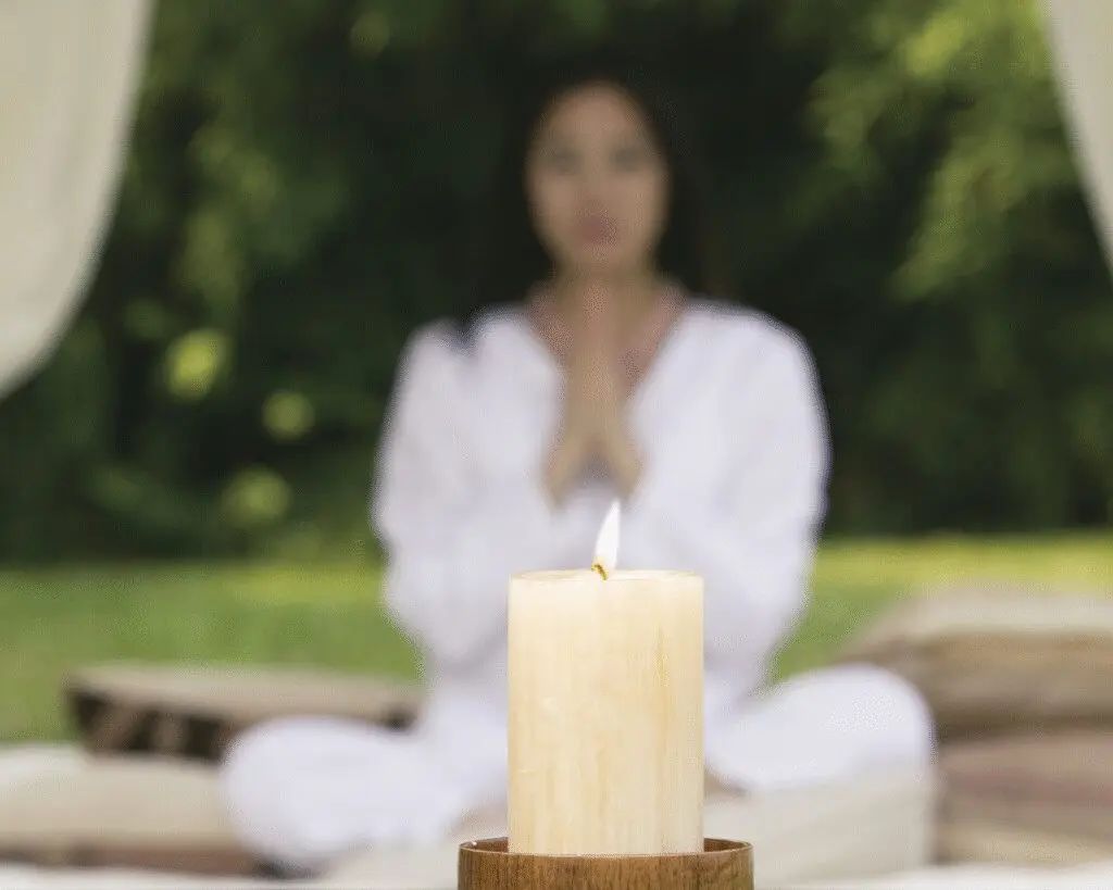 Woman meditating behind a candle